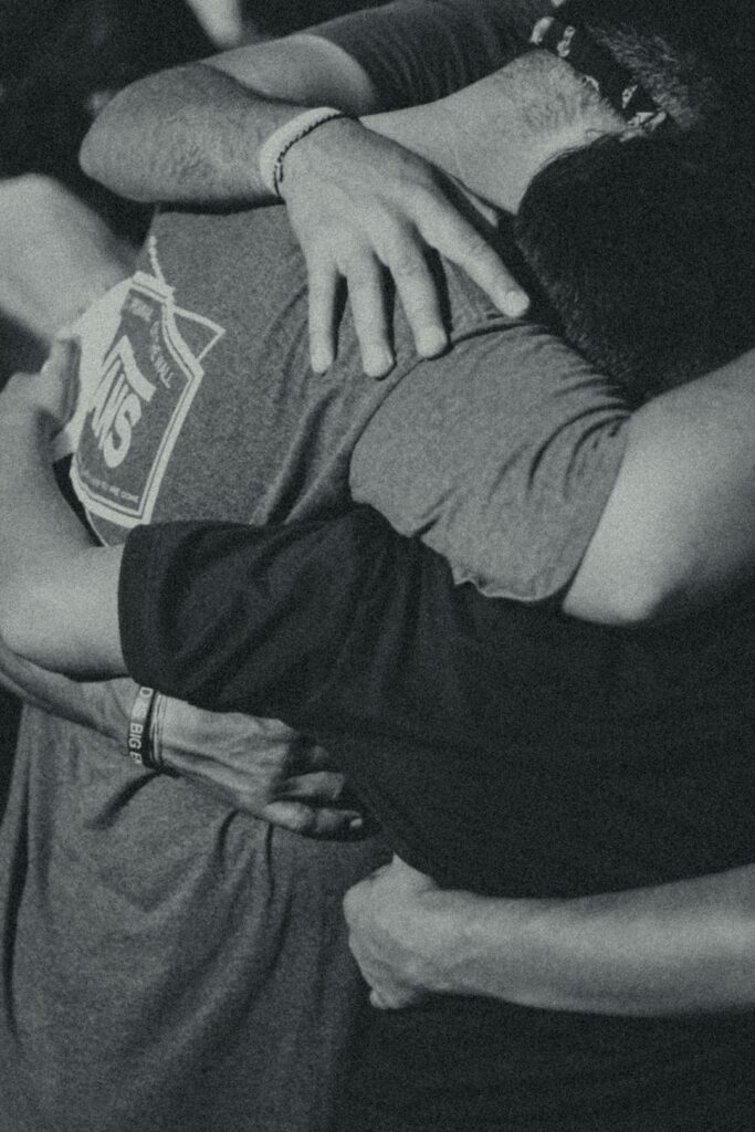 grayscale photography of men doing group hug