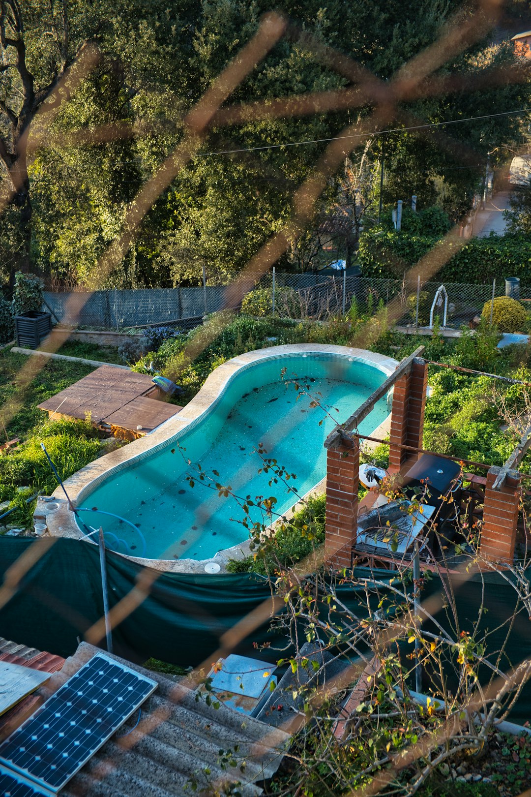 a pool surrounded by trees and a fence