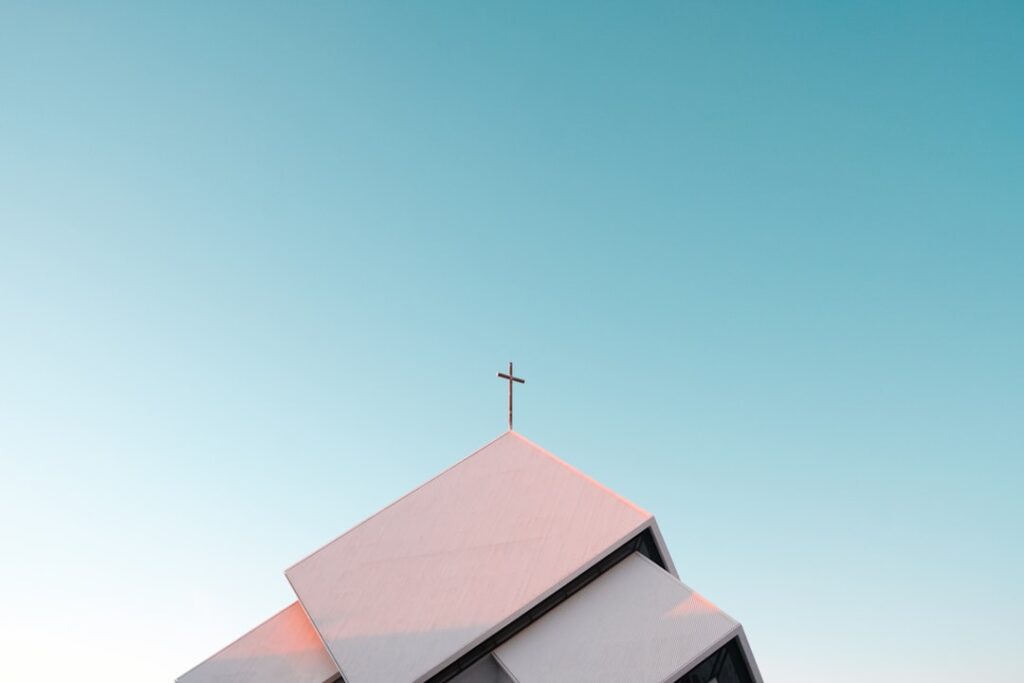 A white church roof with a cross against a clear blue sky